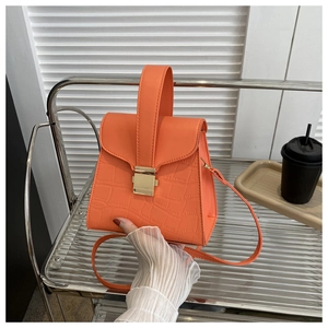 Detail of orange faux leather handbag showing crocodile texture and gold metal buckle