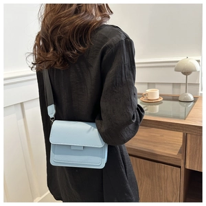 Bolso bandolera cuadrado azul claro con correa ancha de tela en un modelo