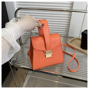 Detail of orange crocodile pattern leather handbag with elegant gold metal buckle closure