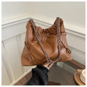 Close-up of brown leather bucket bag with silver chain strap and bow detailing