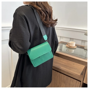 Bolso bandolera de cuero verde con correa ancha negra en modelo para ver tamaño y ajuste