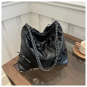Detail of black cloud bucket bag with drawstring closure and leather bow accents