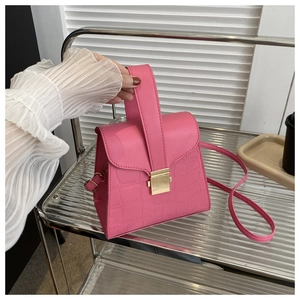 Detail of bright pink PU handbag with crocodile pattern finish and gold buckle