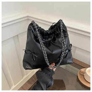 Close-up of black leather bucket bag with drawstring closure and bow details