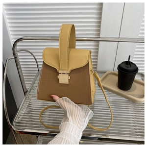 Detail of yellow and brown crocodile embossed handbag with gold buckle and top handle