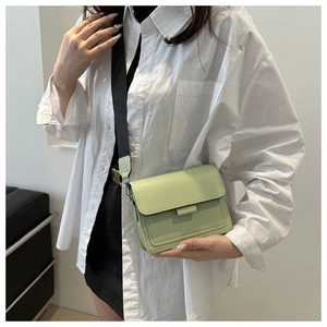 Bolso cuadrado verde pistacho llevado como bandolera con correa ancha de nylon negro