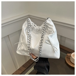 Close-up of white pleated bucket bag with bow details and silver chain strap
