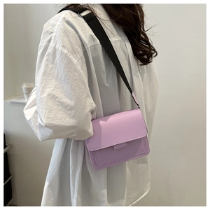 Detalle de un bolso bandolera violeta claro con correa ancha de nailon negro ajustable