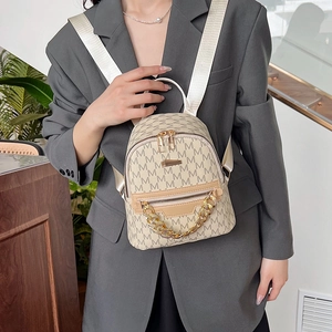 Beige monogram mini backpack with gold chain detail and adjustable straps on model