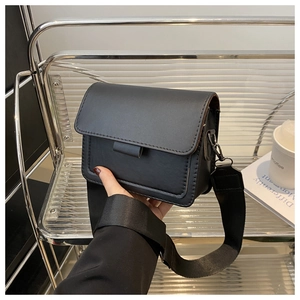 Detalle de bolso cuadrado negro mate con correa de lona ancha ajustable para mujeres