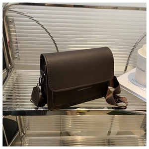 Detalle de bolso bandolera cuadrado marrón oscuro con correa ancha de tela y ganchos