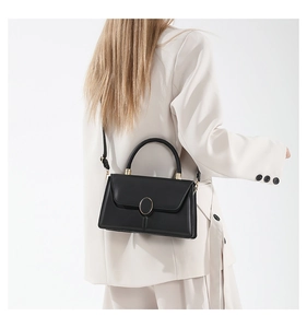 Détail du sac à bandoulière en cuir noir minimaliste avec boucle en métal doré de forme ovale