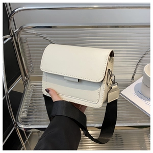Detalle del bolso bandolera de cuero blanco crema con correa ancha negra y herrajes