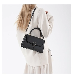 Détails du fermoir ovale doré et des surpiqûres sur un sac à main minimaliste en cuir noir