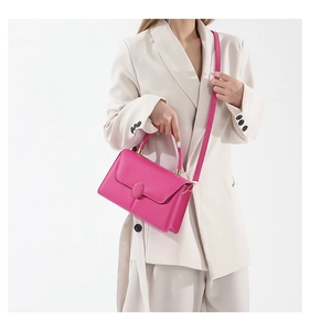 Dettaglio borsa a tracolla fucsia con fibbia dorata su modella con blazer bianco sporco