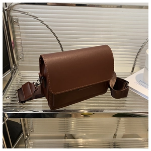 Primer plano de un bolso bandolera cuadrado de cuero marrón oscuro con correa ancha