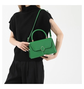 Dettaglio della borsa in pelle verde con chiusura dorata e texture liscia