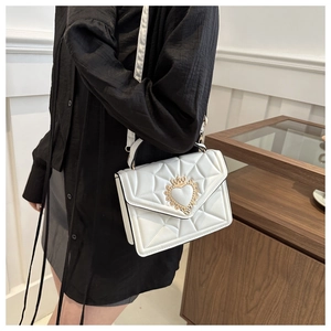 Chic white quilted crossbody bag with gold crown heart buckle worn by a model