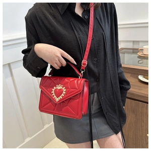 Detail of red quilted leather bag with ornate golden heart crown clasp on the flap
