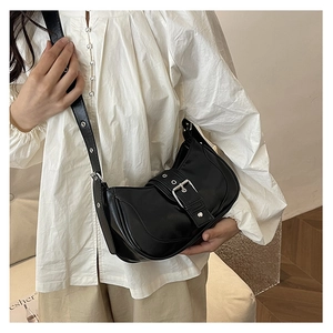 Sac à bandoulière noir tendance avec boucle métallique porté avec un chemisier blanc