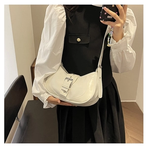 Détail d'un sac demi-lune blanc crème avec un design élégant à boucle métallique