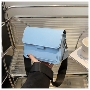 Detalle de bolso cuadrado de cuero azul claro con correa ancha negra estilo casual