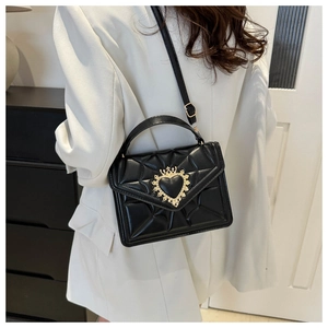 Close-up of black quilted small square bag with golden heart crown metal clasp detail