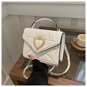 Detailed view of white quilted crossbody bag with heart crown buckle and gold hardware
