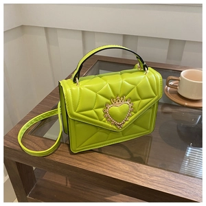 Detail of neon green quilted bag featuring a golden heart crown buckle and radial stitching