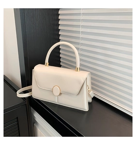 Detail view of the cream leather crossbody bag with top handle and gold round metal lock