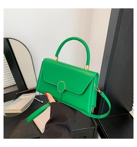 Detail of green trapezoid flap handbag with gold buckle and curved top handle