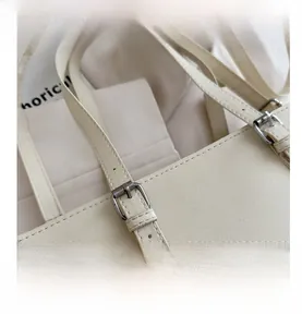 Detail of cross-grain textured leather shoulder bag with adjustable silver metal buckle