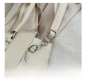 Close-up of durable silver hardware hook and crossgrain leather strap on cream handbag