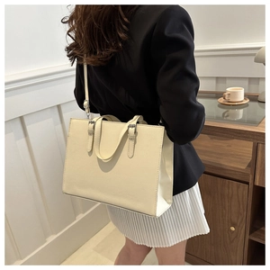 Close-up of cream PU leather tote bag featuring refined crosshatch texture and silver hardware