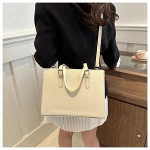Close-up of beige crossbody tote bag with adjustable strap and silver metal hardware