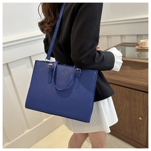 Detail of blue tote bag showing cross-grain texture with metal hardware and shoulder strap