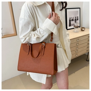 Detail of caramel brown textured leather tote bag with silver hardware and shoulder strap