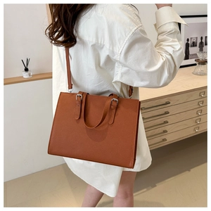 Brown leather tote bag shown from side-rear view with thin adjustable shoulder strap