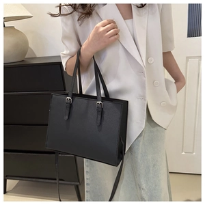 Detail of black cross-grain textured tote bag with adjustable metal buckle on straps