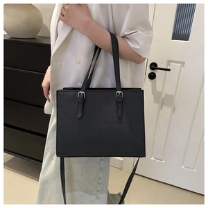 Detail showing Saffiano leather texture and silver buckle accents on the black tote bag