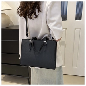 Close-up of minimalist black pebbled leather tote bag with silver hardware and shoulder strap