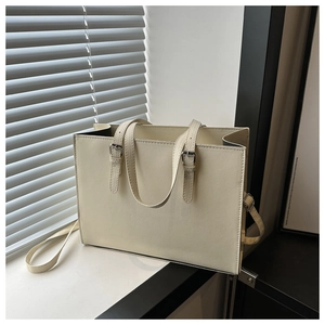 Detail of off-white Saffiano leather tote bag showing fine texture and buckled handles