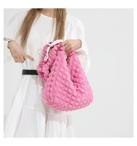Detail of pink bubble texture tote bag with white drawstring closure on white dress