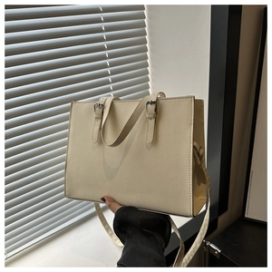 Detail of beige cross-grain leather tote bag with silver hardware and adjustable strap