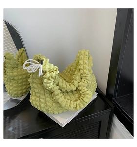 Gros plan sur le tissu gaufré vert clair et le cordon décoratif blanc sur le sac à main