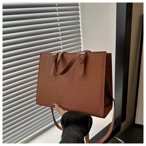 Close-up of brown Saffiano texture tote bag with silver adjustable buckles and strap
