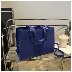 Detail of navy blue tote bag featuring textured crossgrain leather and metal buckles