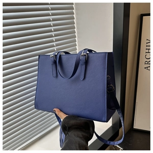 Macro view of blue faux leather tote bag with cross pattern texture and silver hardware