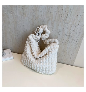 Détail de la texture bulle blanche et du tissu plissé doux sur la bandoulière du sac