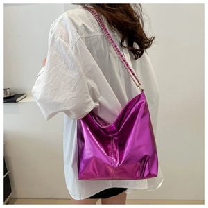Detail of metallic purple tote bag with chain strap worn on white shirt by model